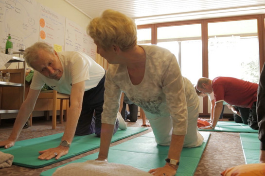 Zwei Personen machen Yoga Übungen auf einer Matte