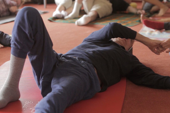 Ein Mann liegt auf einer Yoga Matte und macht Übungen