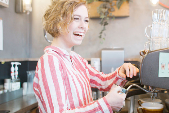 Eine Frau macht einen Kaffee an einer Siebträgermaschine