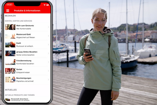 Eine blonde Frau steht mit ihrem Handy am Flensburger Hafen