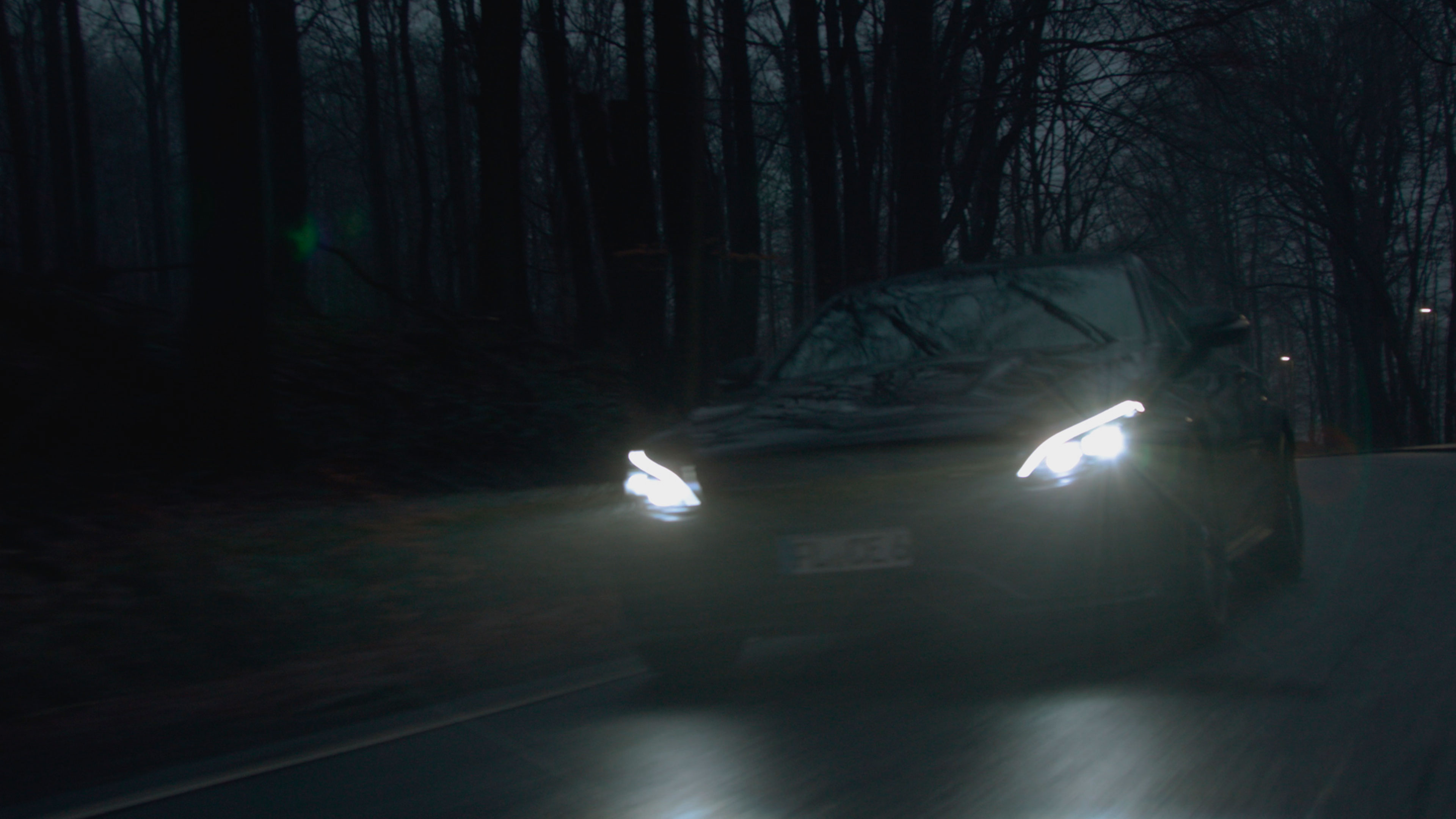 Ein Mercedes Benz fährt im dunkeln auf einer Landstraße