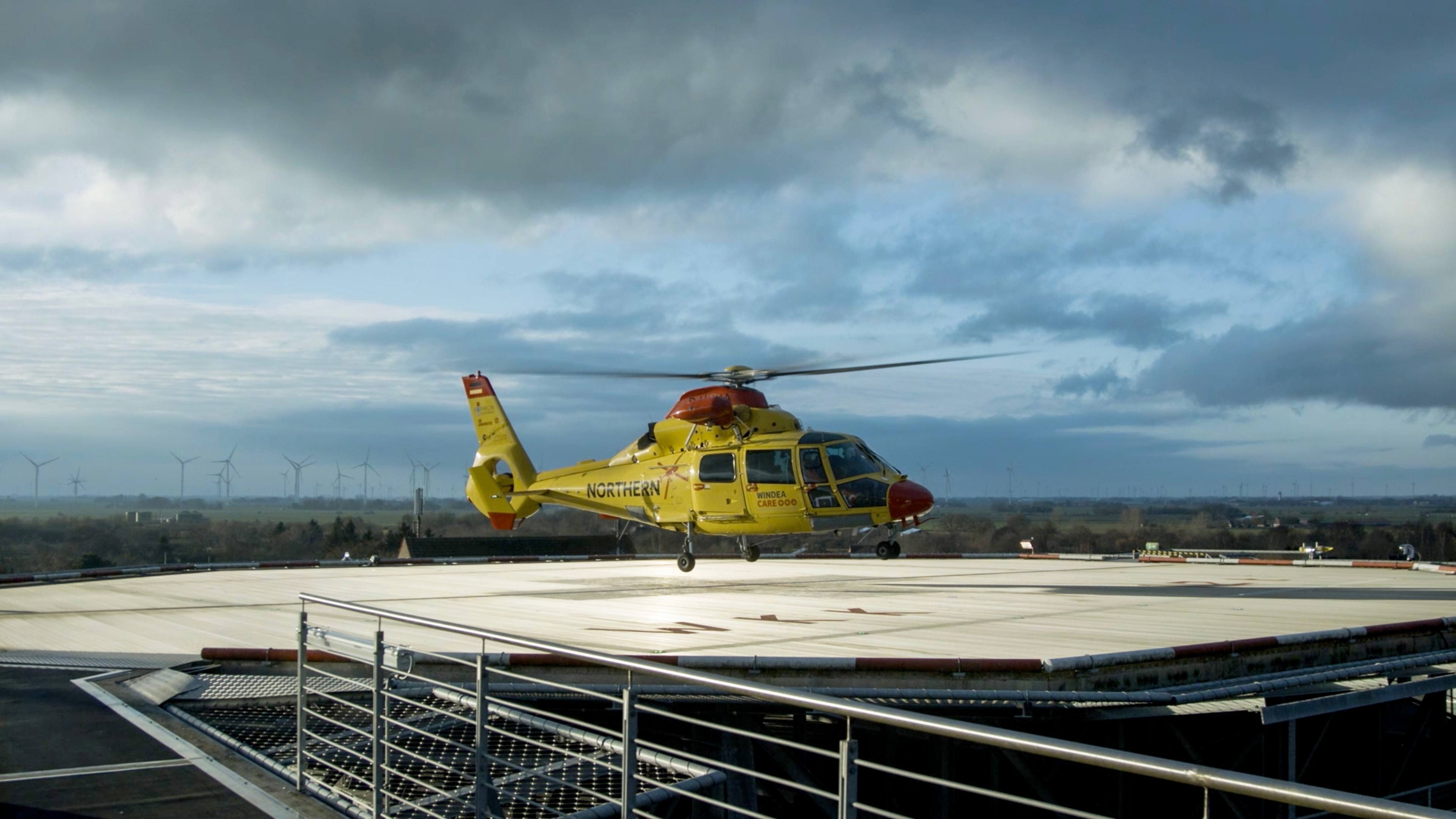 Ein gelber Hubschrauber landet auf einem Krankenhausdach
